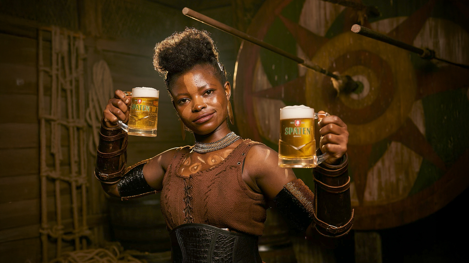 A warrior-styled model raises two Spaten mugs on the campaign set.